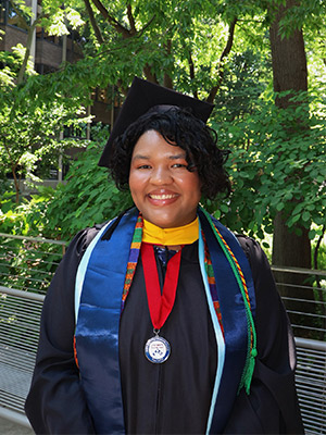 Woman in graduation regalia posing outside