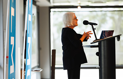 Woman with grey hair at podium with a microphone