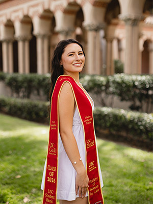 Woman with graduation stoll poses outside