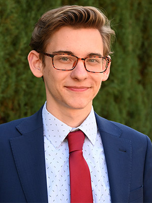 Man in blue suit and glasses posing outside