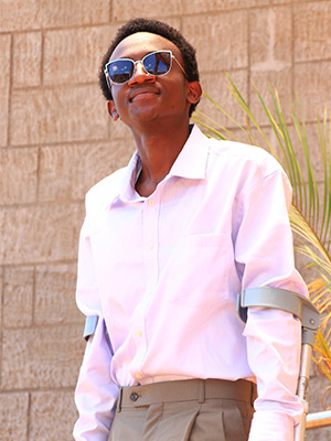 Man poses outside in a pink shirt and sunglasses