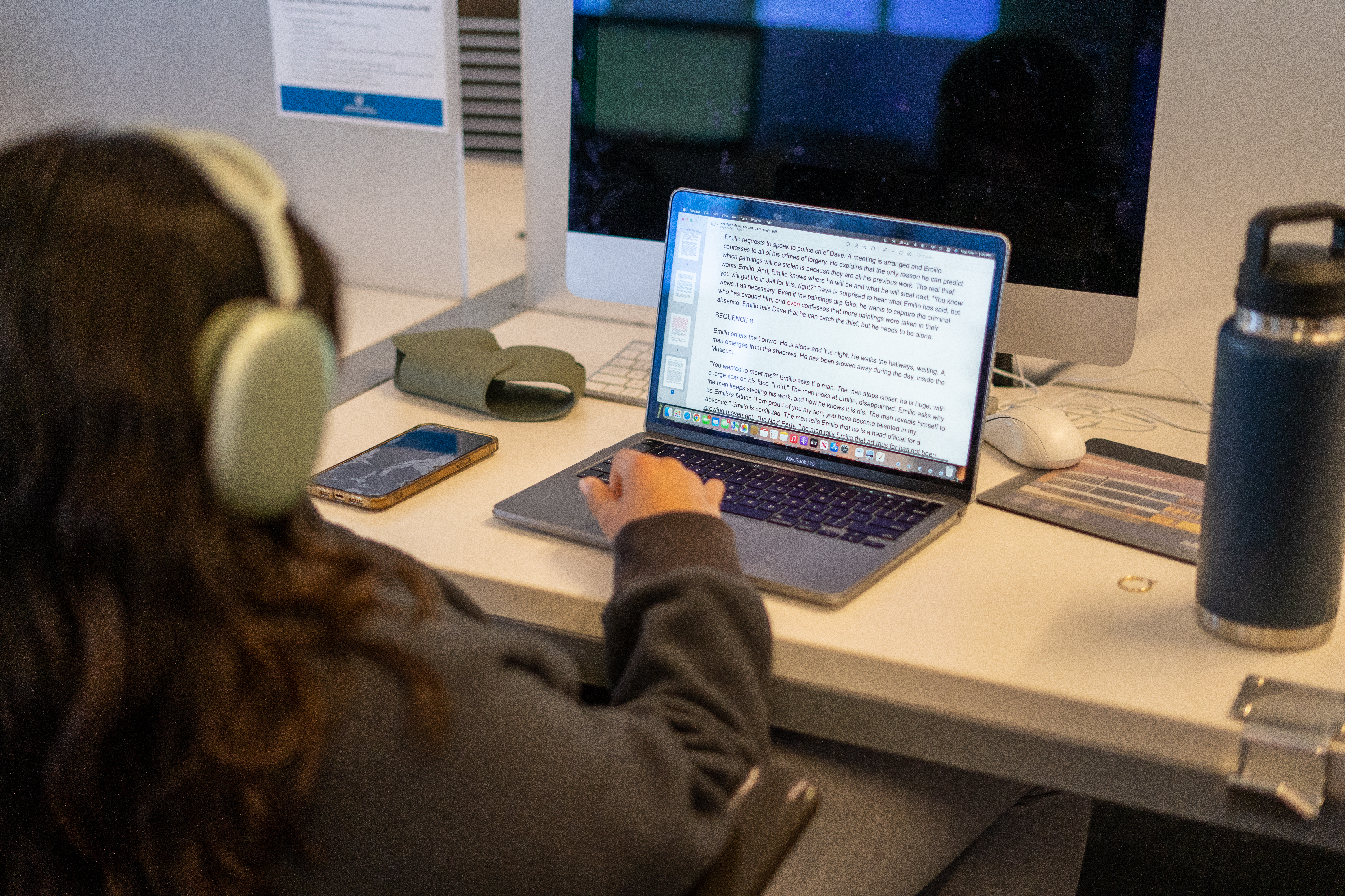 A student wearing headphones sits in front of a laptop.