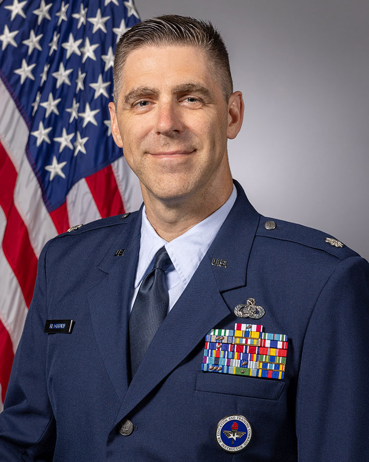 Aaron Blackburn in uniform and standing in front of the American flag