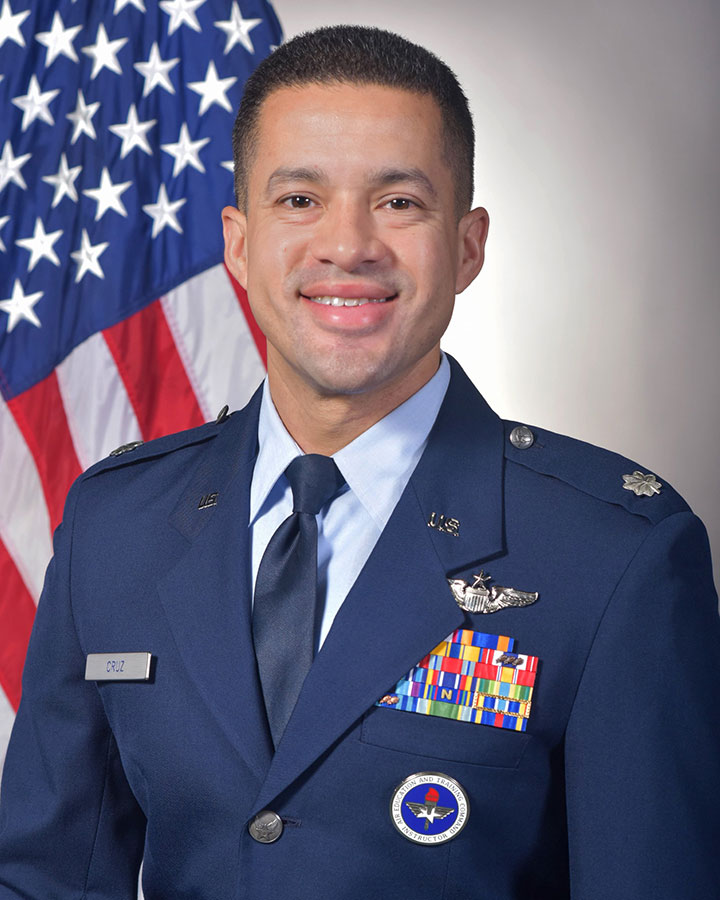 Adrian Cruz in uniform and standing in front of the American flag
