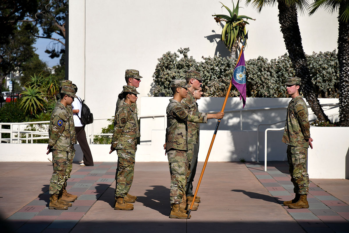 AFROTC cadets in combat attire standing in formation and holding the US Air Force flag