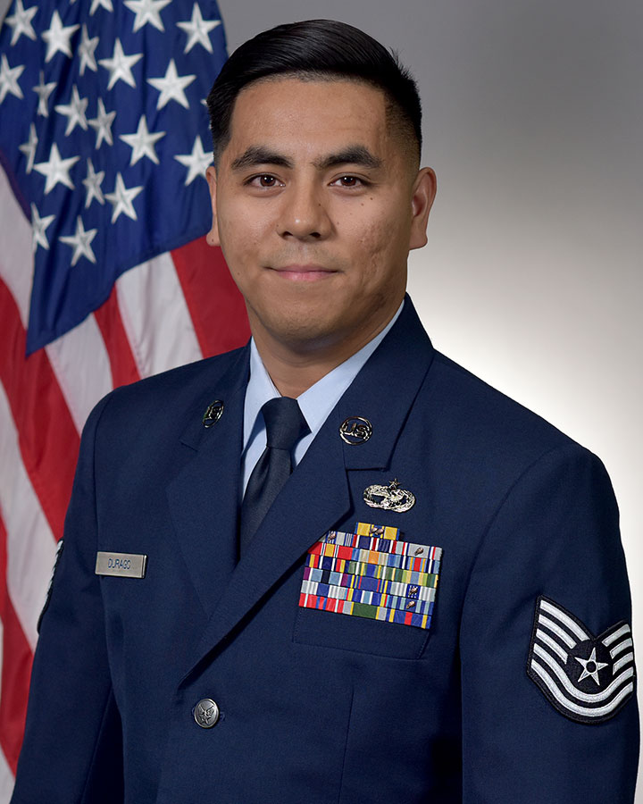 John Paul Durago in uniform and standing in front of the American flag