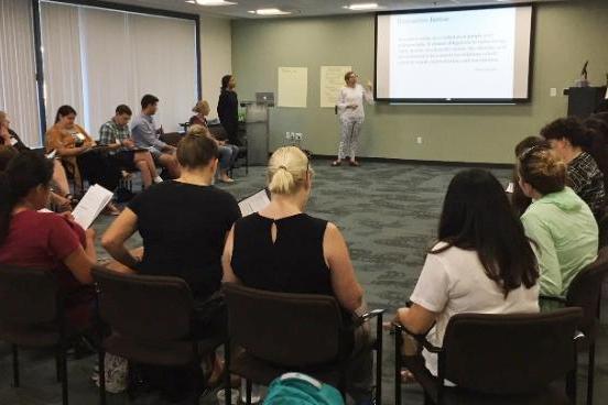 A lecture with attendees sitting in a semi-circle around the speaker