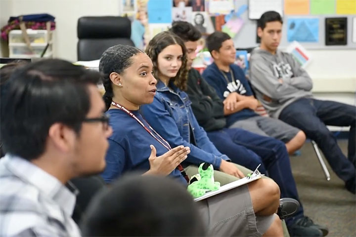 A teacher speaking in a classroom of seated students