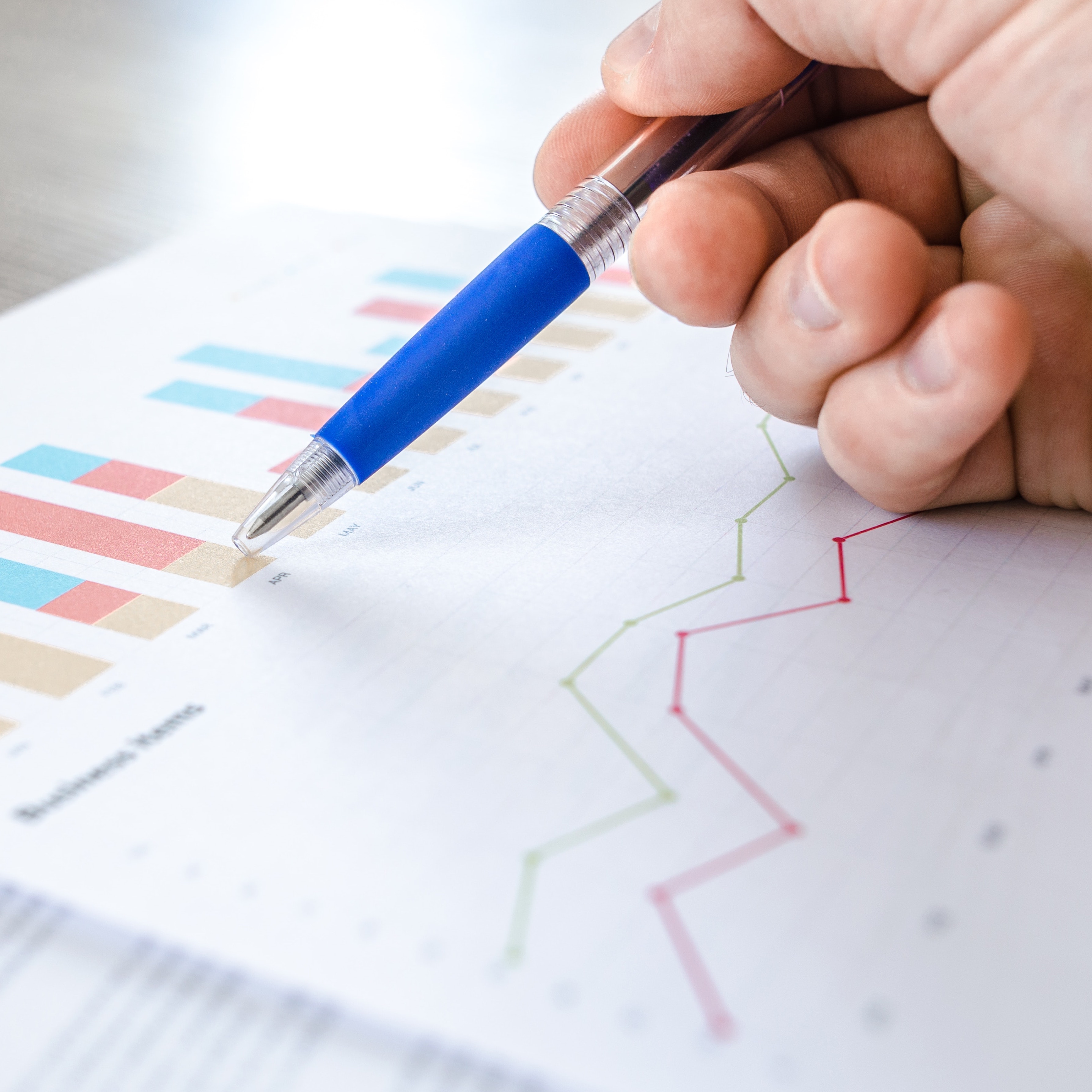 hand holding pen looking at statistics