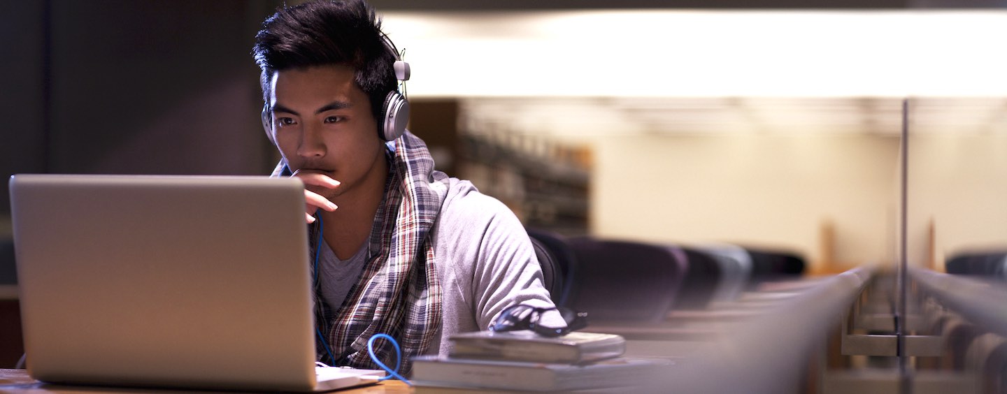 male student on a computer wearing headphones