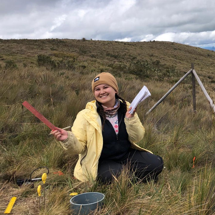 Sabriya Seid in an open field with measurement tools and notepads