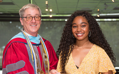 A student dressed up and the president in regalia pose during the annual Academic Awards convocation.