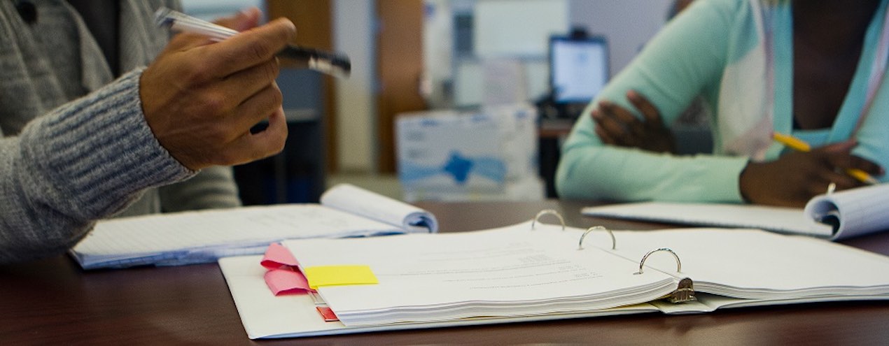 two people at a table with notebooks, working