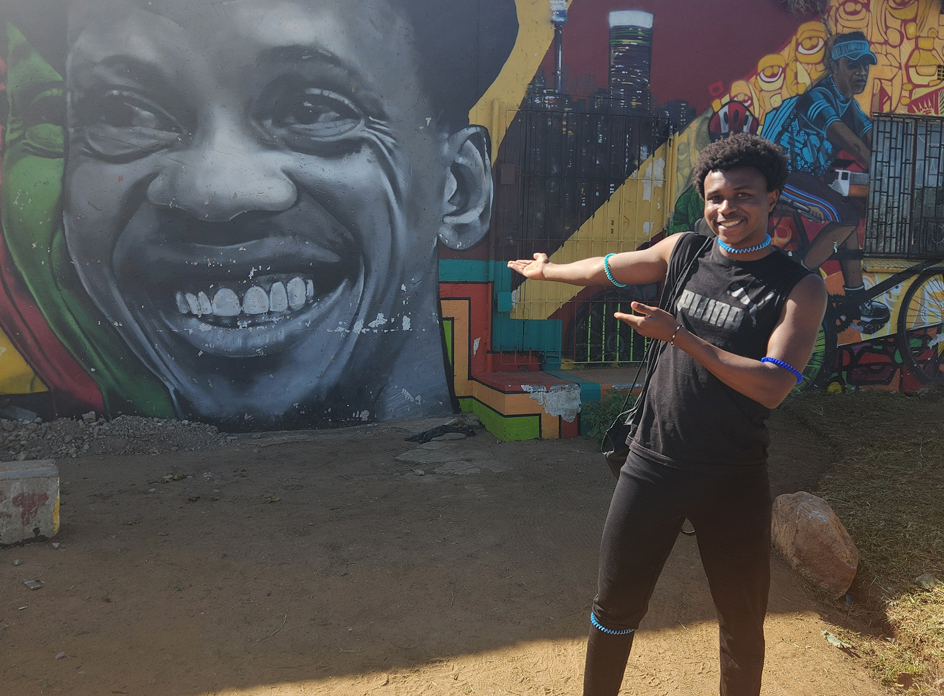 A student poses outside in front of a colorful mural on a global immersion experience.